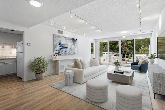 2774 S Ocean Blvd Unit 106, Palm Beach, FL 33480 - living room with track lighting, light wood finished floors, baseboards, and a textured ceiling