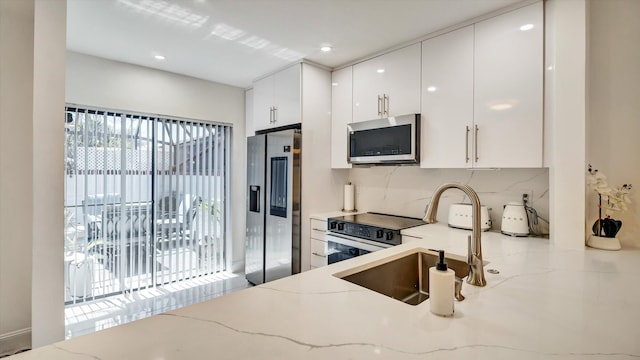 6320 Wedgewood Ter Unit 6320, Tamarac, FL 33321 - kitchen featuring appliances with stainless steel finishes, tasteful backsplash, a sink, light stone counters, and white cabinetry