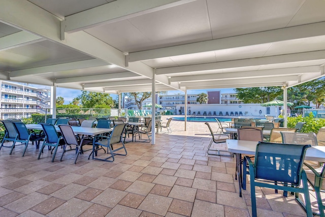 view of patio / terrace with fence, outdoor dining space, and a community pool