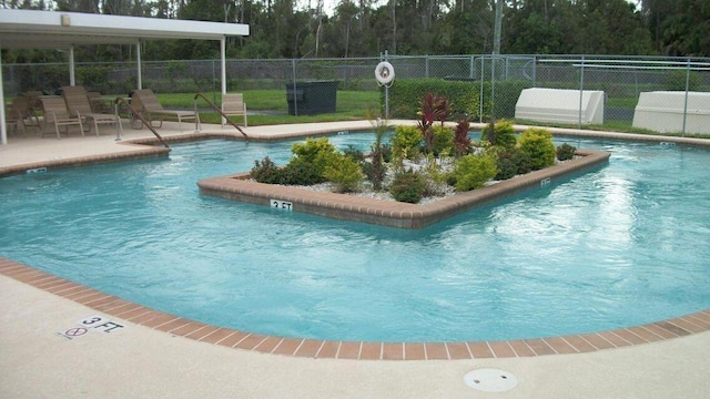 pool with fence, a patio area, and a forest view