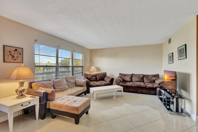 living area with light tile patterned floors, a textured ceiling, and visible vents
