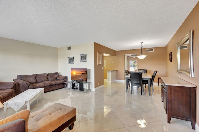 living area with baseboards, a textured ceiling, and visible vents