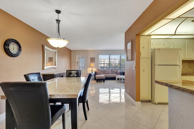 dining area with light tile patterned floors, baseboards, and a textured ceiling