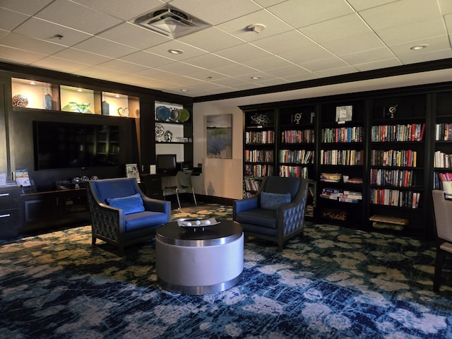 living area with visible vents, carpet flooring, and wall of books