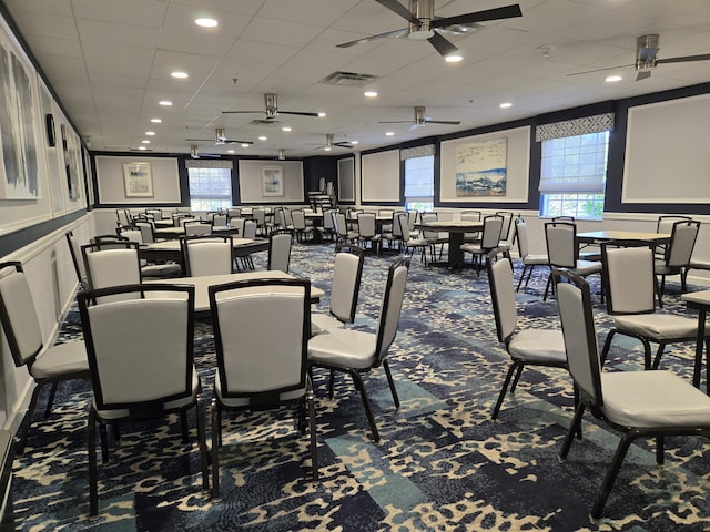 carpeted dining area featuring visible vents, a ceiling fan, and a drop ceiling