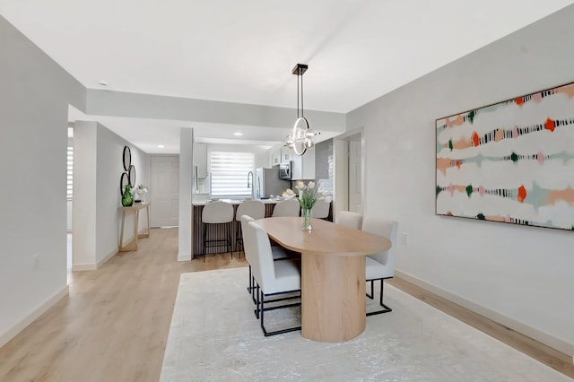 6049 Balboa Cir Unit 106, Boca Raton, FL 33433 - dining area with baseboards, light wood-style flooring, and a notable chandelier