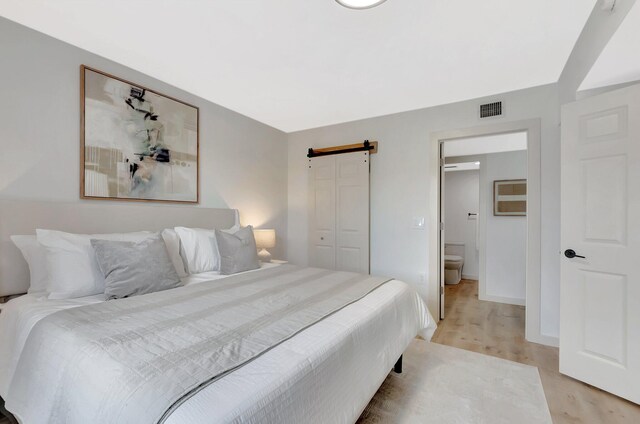 6049 Balboa Cir Unit 106, Boca Raton, FL 33433 - bedroom featuring a barn door, light wood-style flooring, baseboards, visible vents, and a closet