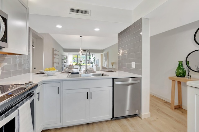 6049 Balboa Cir Unit 106, Boca Raton, FL 33433 - kitchen with appliances with stainless steel finishes, a sink, light wood finished floors, a peninsula, and visible vents