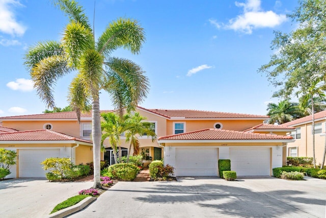 mediterranean / spanish house with a tiled roof, a garage, driveway, and stucco siding