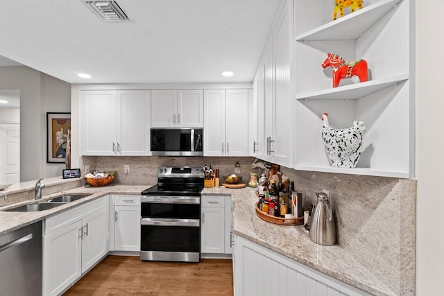 kitchen featuring visible vents, open shelves, white cabinets, a sink, and appliances with stainless steel finishes