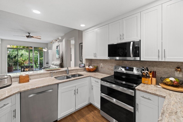 kitchen with a ceiling fan, tasteful backsplash, a sink, white cabinets, and stainless steel appliances