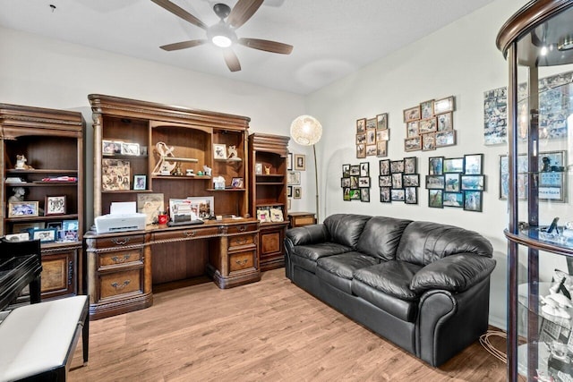 office area with built in desk, ceiling fan, and light wood-style flooring
