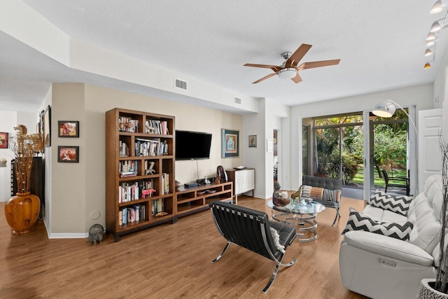 living room with a ceiling fan, a textured ceiling, visible vents, and wood finished floors
