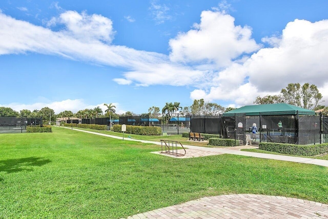 view of home's community with a lawn, fence, and a tennis court