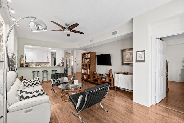living room with baseboards, a ceiling fan, wood finished floors, and visible vents