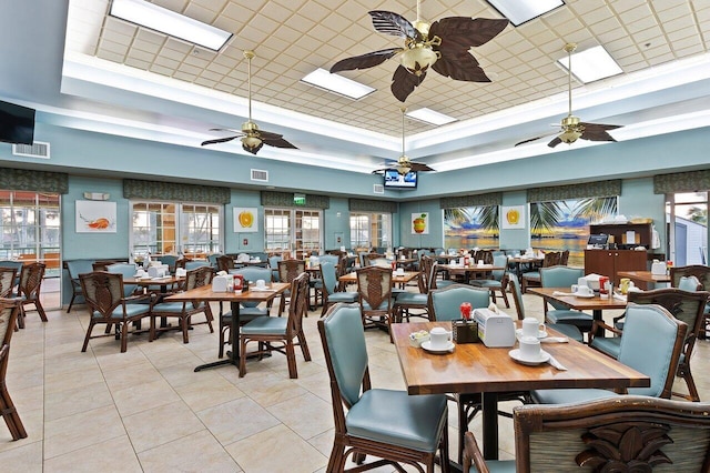 dining room with visible vents, a ceiling fan, light tile patterned flooring, and a tray ceiling