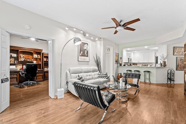 living room with ceiling fan, built in desk, and light wood-style floors