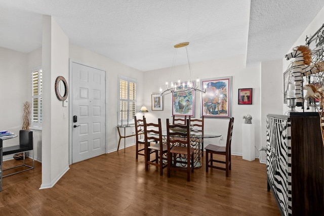 dining room featuring a textured ceiling, baseboards, a notable chandelier, and wood finished floors