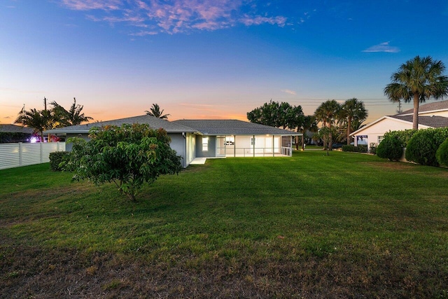 back of house featuring a yard, fence, and stucco siding