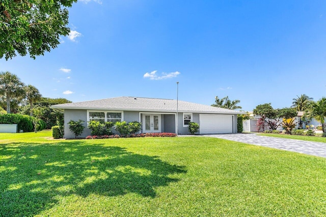 ranch-style house featuring a garage, a front lawn, decorative driveway, stucco siding, and french doors