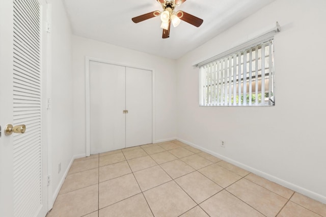 unfurnished bedroom with baseboards, a ceiling fan, a closet, and tile patterned floors