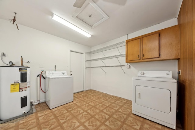 laundry room with electric water heater, attic access, light floors, washing machine and clothes dryer, and cabinet space