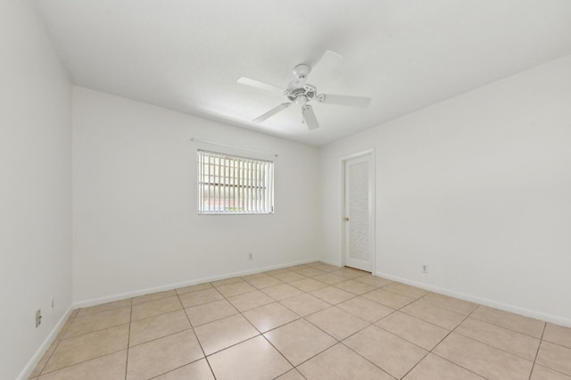 spare room featuring light tile patterned floors, baseboards, and ceiling fan