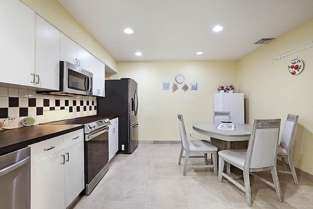503 Vision Ct, Palm Beach Gardens, FL 33418 - kitchen with white cabinets, dark countertops, stainless steel appliances, recessed lighting, and visible vents