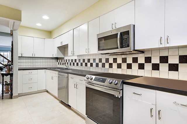 503 Vision Ct, Palm Beach Gardens, FL 33418 - kitchen with dark countertops, tasteful backsplash, a sink, white cabinets, and stainless steel appliances