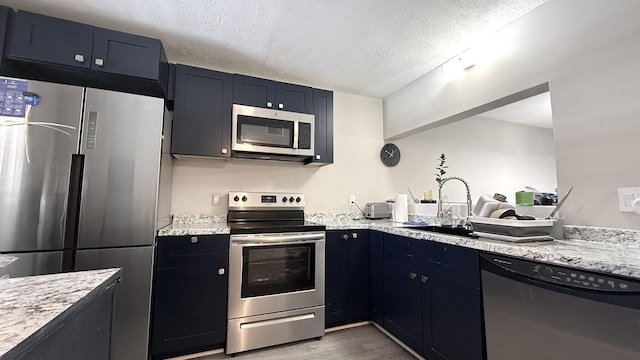 2925 SW 22nd Ave Unit 2030, Delray Beach, FL 33445 - kitchen featuring appliances with stainless steel finishes, wood finished floors, a sink, a textured ceiling, and light stone counters