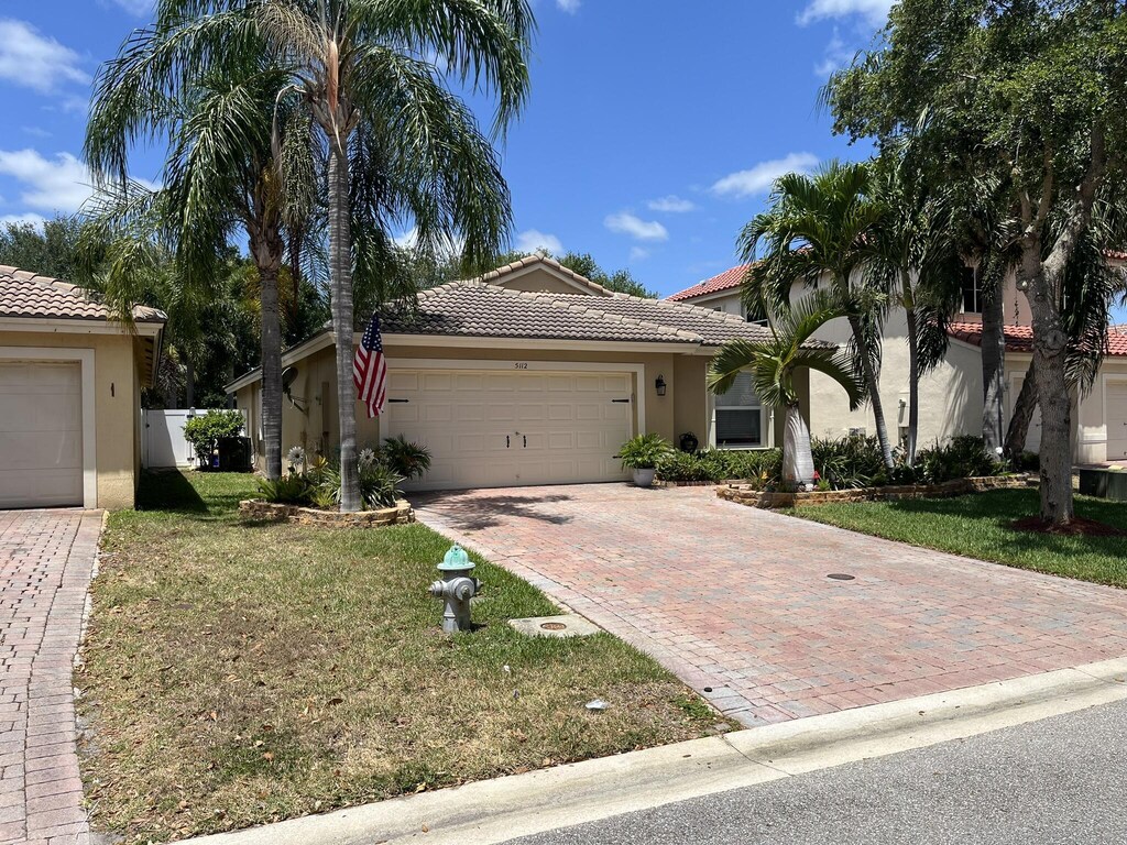 5112 Victoria Cir, West Palm Beach, FL 33409 - view of front of home with an attached garage, stucco siding, a front yard, decorative driveway, and a tiled roof