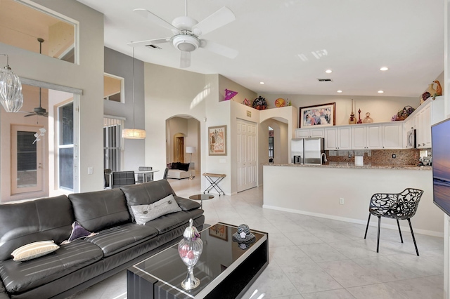 living room featuring visible vents, a ceiling fan, high vaulted ceiling, arched walkways, and light tile patterned floors