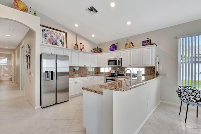 kitchen featuring light tile patterned floors, appliances with stainless steel finishes, tasteful backsplash, and arched walkways