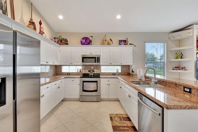 kitchen featuring a sink, stainless steel appliances, a peninsula, light tile patterned floors, and backsplash