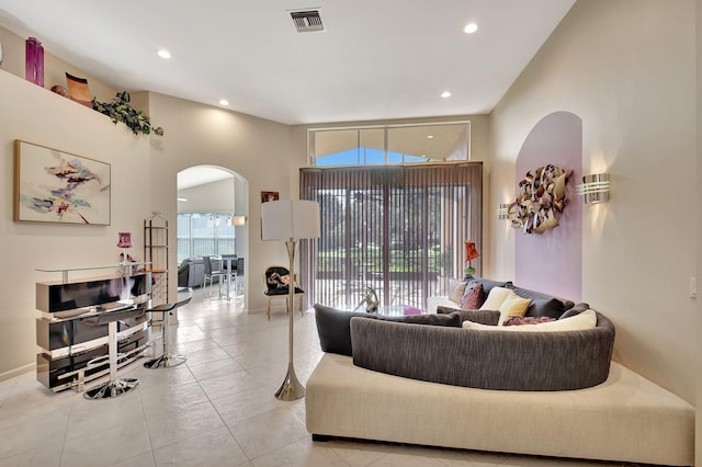 living area with light tile patterned floors, arched walkways, recessed lighting, and visible vents
