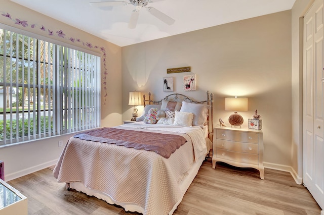 bedroom featuring light wood-style floors, baseboards, ceiling fan, and a closet