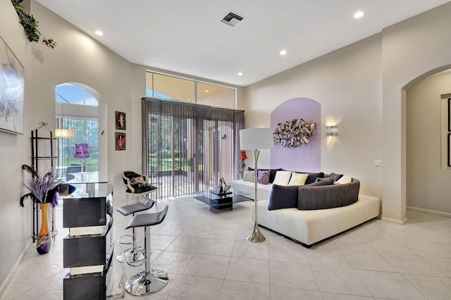 living room featuring arched walkways, baseboards, visible vents, and recessed lighting