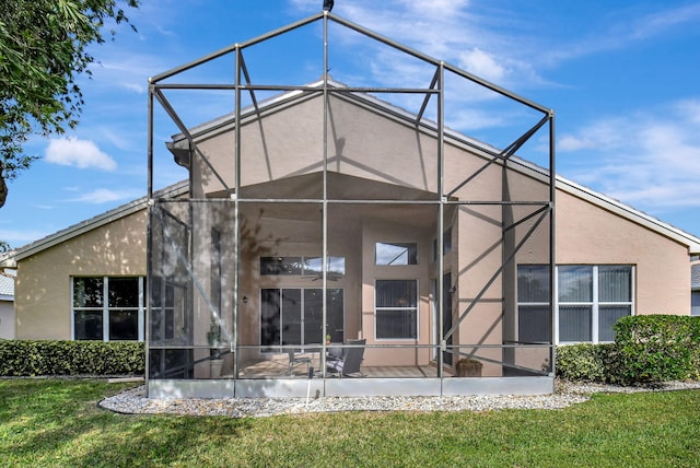rear view of property featuring a lawn, glass enclosure, and stucco siding