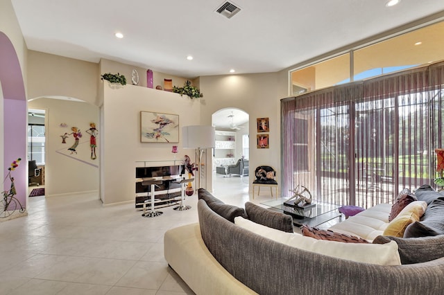 living room with arched walkways, recessed lighting, light tile patterned flooring, and visible vents