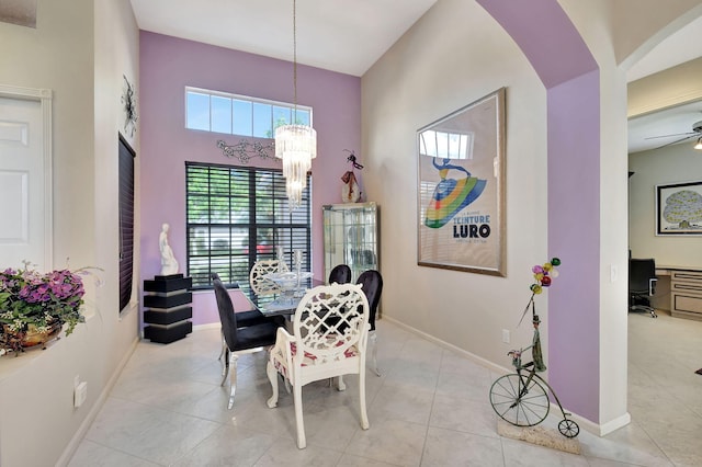 tiled dining area with plenty of natural light, arched walkways, baseboards, and ceiling fan with notable chandelier