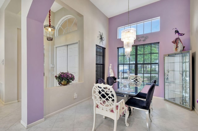 dining space featuring baseboards, a high ceiling, tile patterned flooring, and a notable chandelier