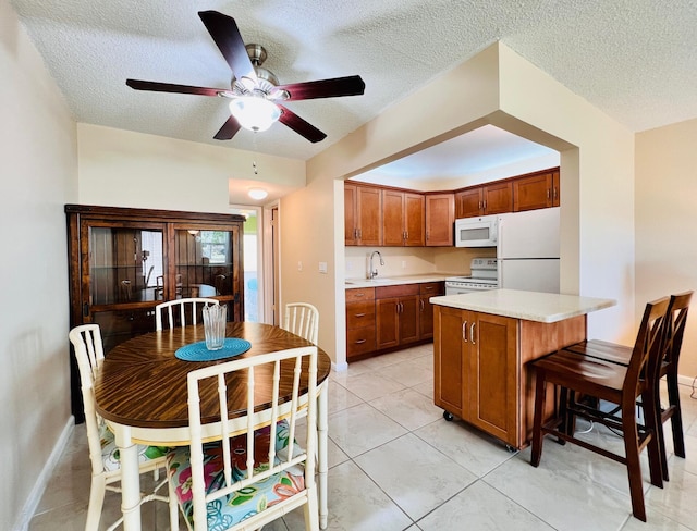 kitchen featuring white appliances, a ceiling fan, a textured ceiling, and light countertops