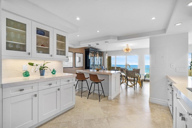 4001 N Ocean Blvd Unit 1108, Boca Raton, FL 33431 - kitchen with white cabinets, recessed lighting, glass insert cabinets, a breakfast bar, and decorative backsplash