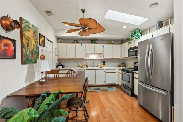 kitchen featuring visible vents, light countertops, a sink, light wood-style flooring, and appliances with stainless steel finishes