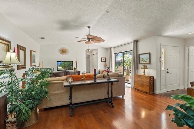 living area with a ceiling fan, a textured ceiling, visible vents, wood finished floors, and lofted ceiling