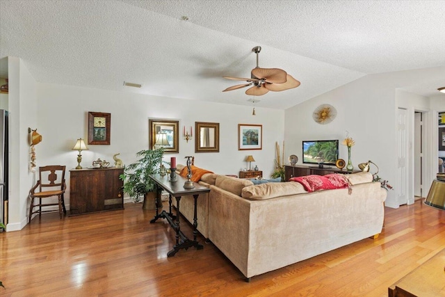 living room with vaulted ceiling, a ceiling fan, wood finished floors, and visible vents
