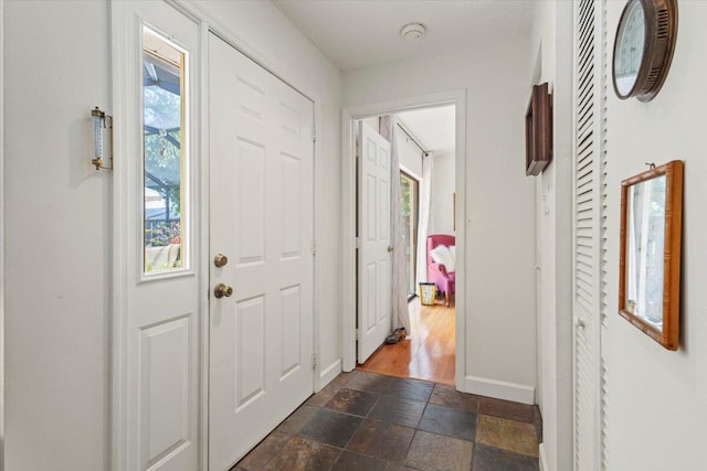 entrance foyer with baseboards and stone tile floors