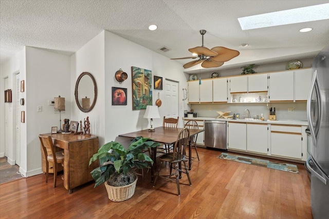 kitchen with light wood-type flooring, light countertops, a sink, stainless steel appliances, and white cabinetry