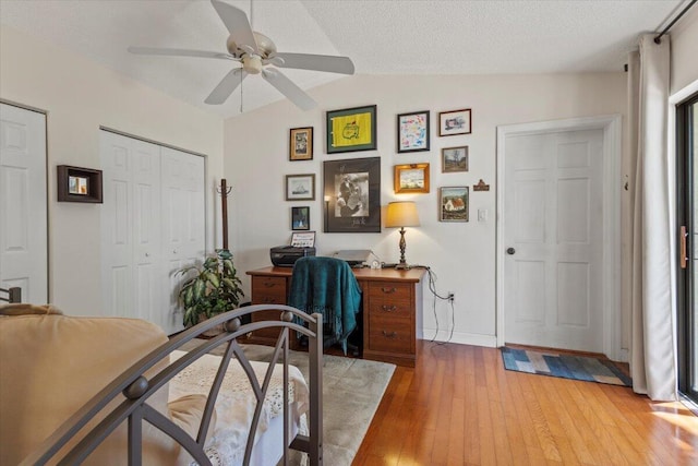 home office featuring light wood-style floors, a ceiling fan, and lofted ceiling