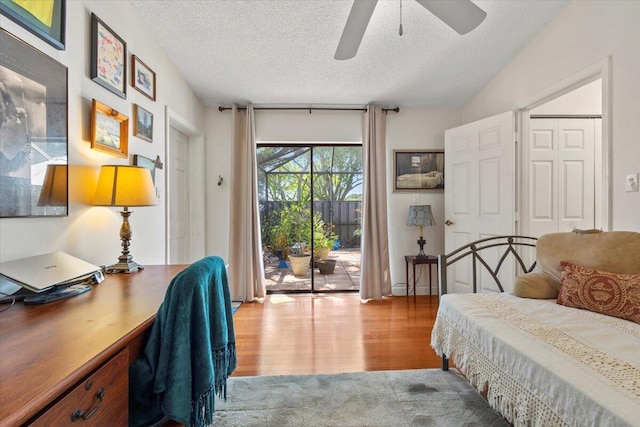 bedroom with a ceiling fan, a textured ceiling, wood finished floors, and access to exterior